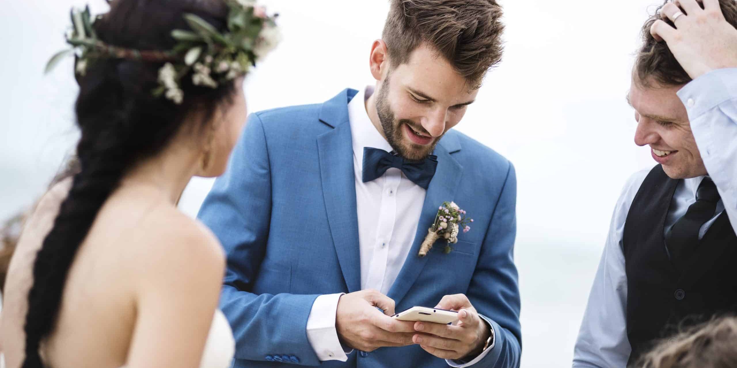 Groom occupied with phone at beach wedding ceremony
