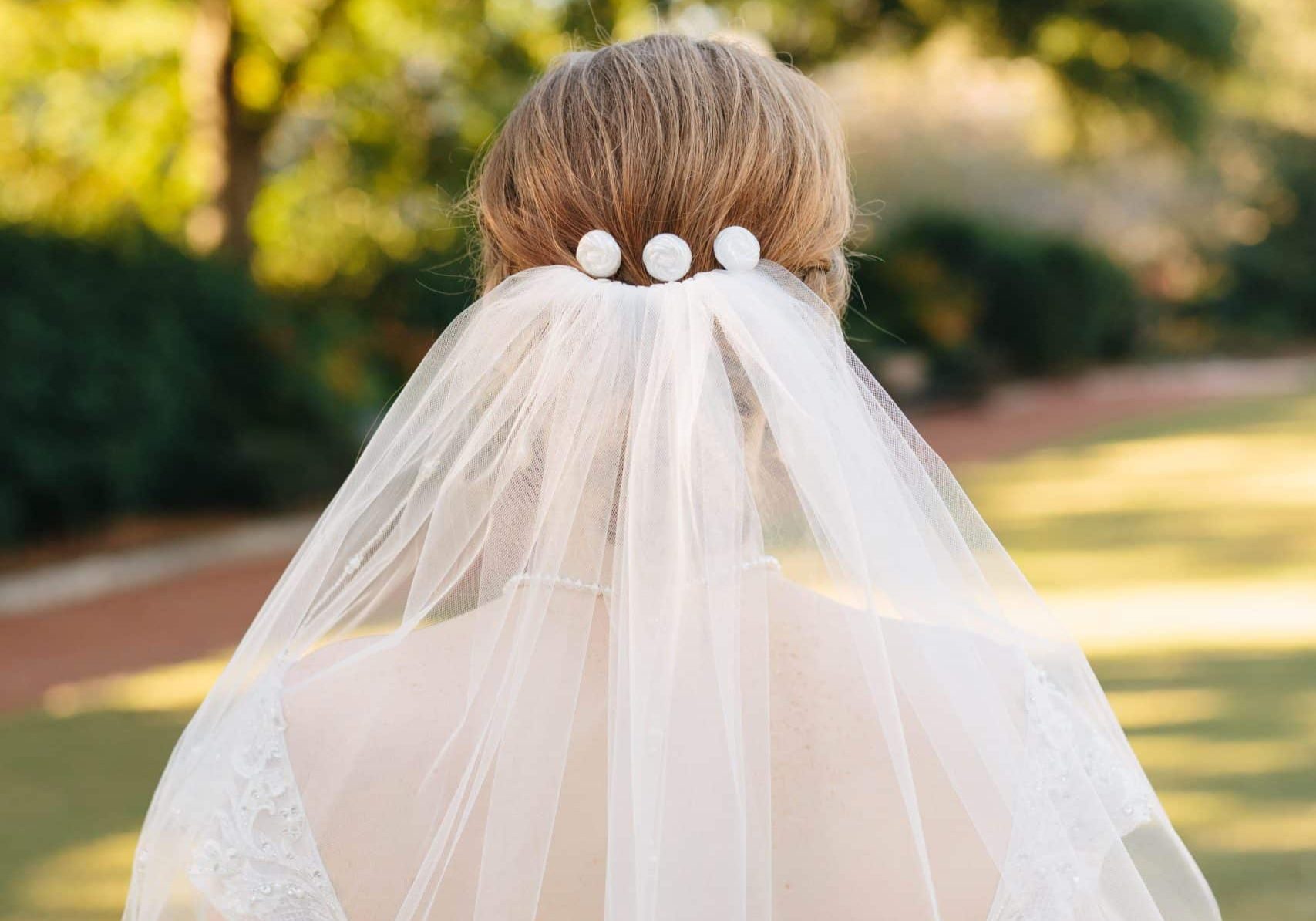 A vertical closeup of bridal hair accessories and a beautiful veil captured in a garden