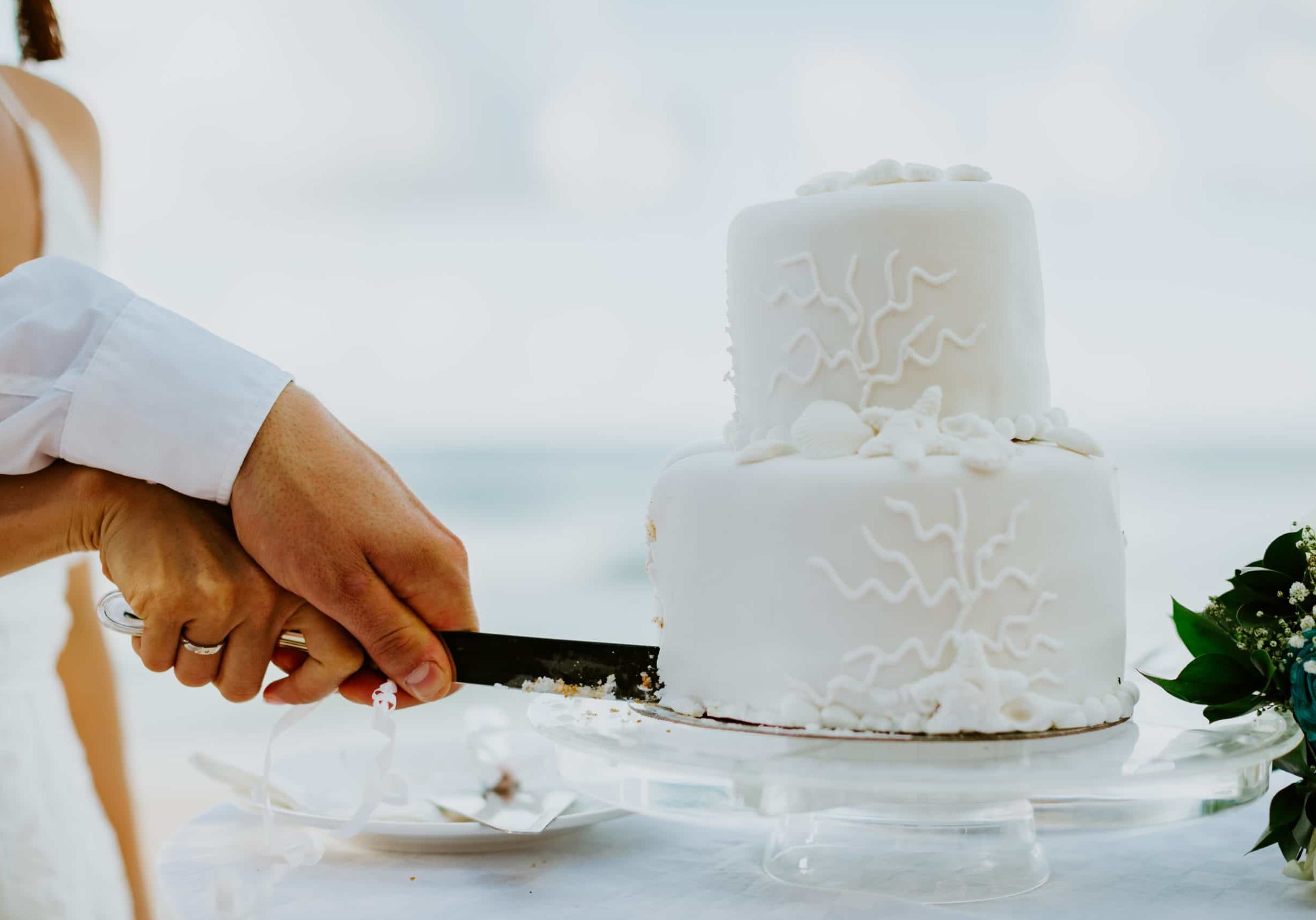 wedding cake cutting on beach. White wedding cake